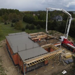 MaG Inwest - Wylewanie betonu na strop domu jednorodzinnego w stanie surowym otwartym z użyciem pompy do betonu, widok z drona na plac budowy.