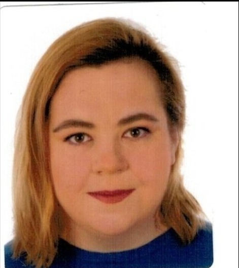 Portret kobiety z blond włosami, ubrana w niebieską bluzkę, na białym tle.