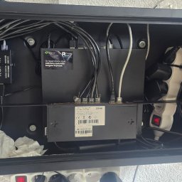 JS.Trade Przemysław Pitura - Otwarta szafka rack z zainstalowanym switchem PoE, rejestratorem Seagate SkyHawk, przedłużaczem HDMI KVM i okablowaniem. Widoczne elementy montażowe i zasilacze.