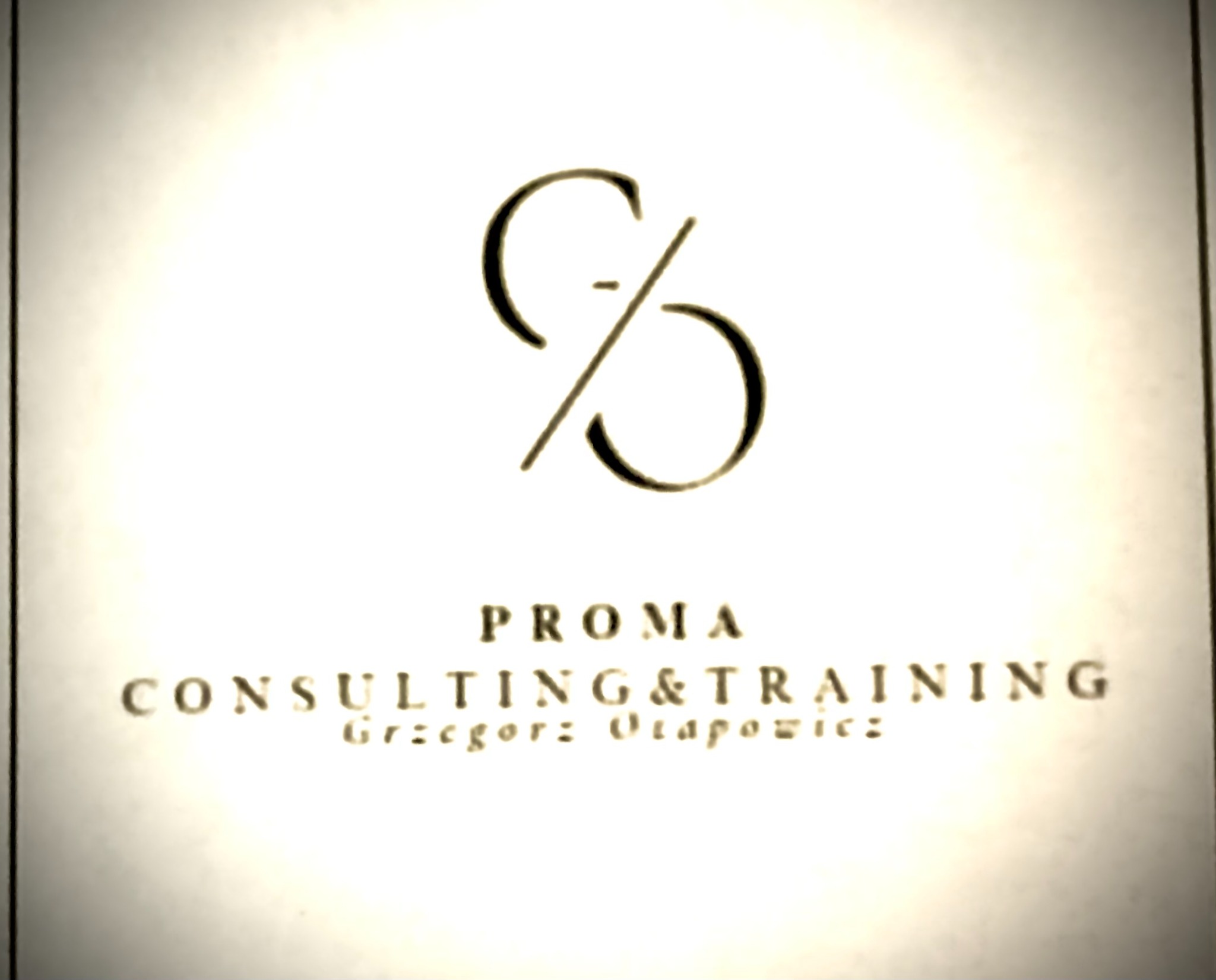 Logo firmy PROMA Consulting & Training z abstrakcyjnym symbolem graficznym i nazwiskiem Grzegorz Otapowicz, w odcieniach sepii na jasnym tle.