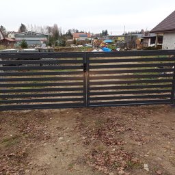 JOGILLA Art Welding - Nowoczesna, dwuskrzydłowa brama wjazdowa z poziomych profili, pomalowana na grafitowy kolor, z widocznym zamkiem i słupkami, na tle zabudowań jednorodzinnych w jesiennej scenerii.