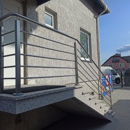 JOGILLA Art Welding - Zewnętrzne schody granitowe z metalową balustradą w Olsztynie, widok z dołu, w tle budynek i zaparkowany samochód.
