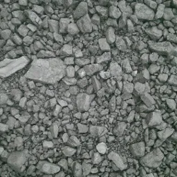 Drobny, szary materiał opałowy o nieregularnych kształtach, wypełniający całą powierzchnię kadru.