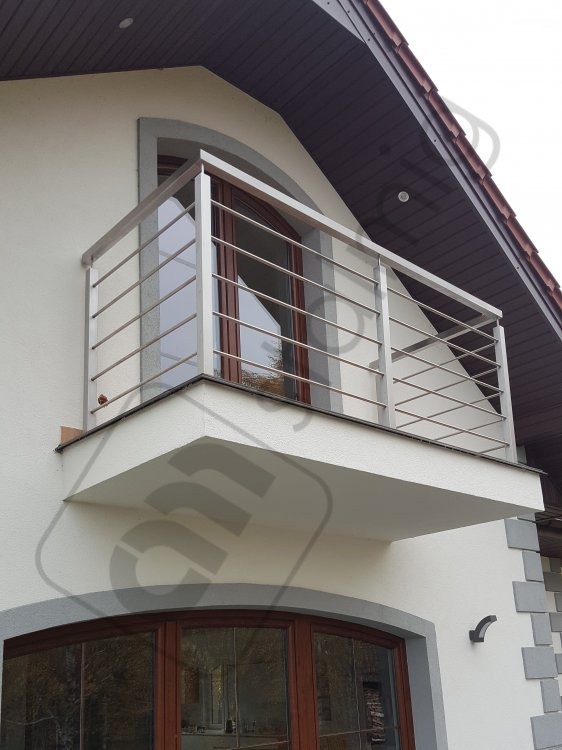 Balkon z nowoczesną, minimalistyczną konstrukcją ze stali nierdzewnej, z poziomymi prętami. Widok z dołu, ukazujący elewację domu z drewnianymi oknami i elementami dekoracyjnymi.