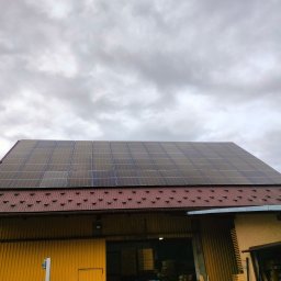 DMS System sp.z o.o. - Panele słoneczne na dachu budynku gospodarczego z blachy trapezowej w pochmurny dzień.