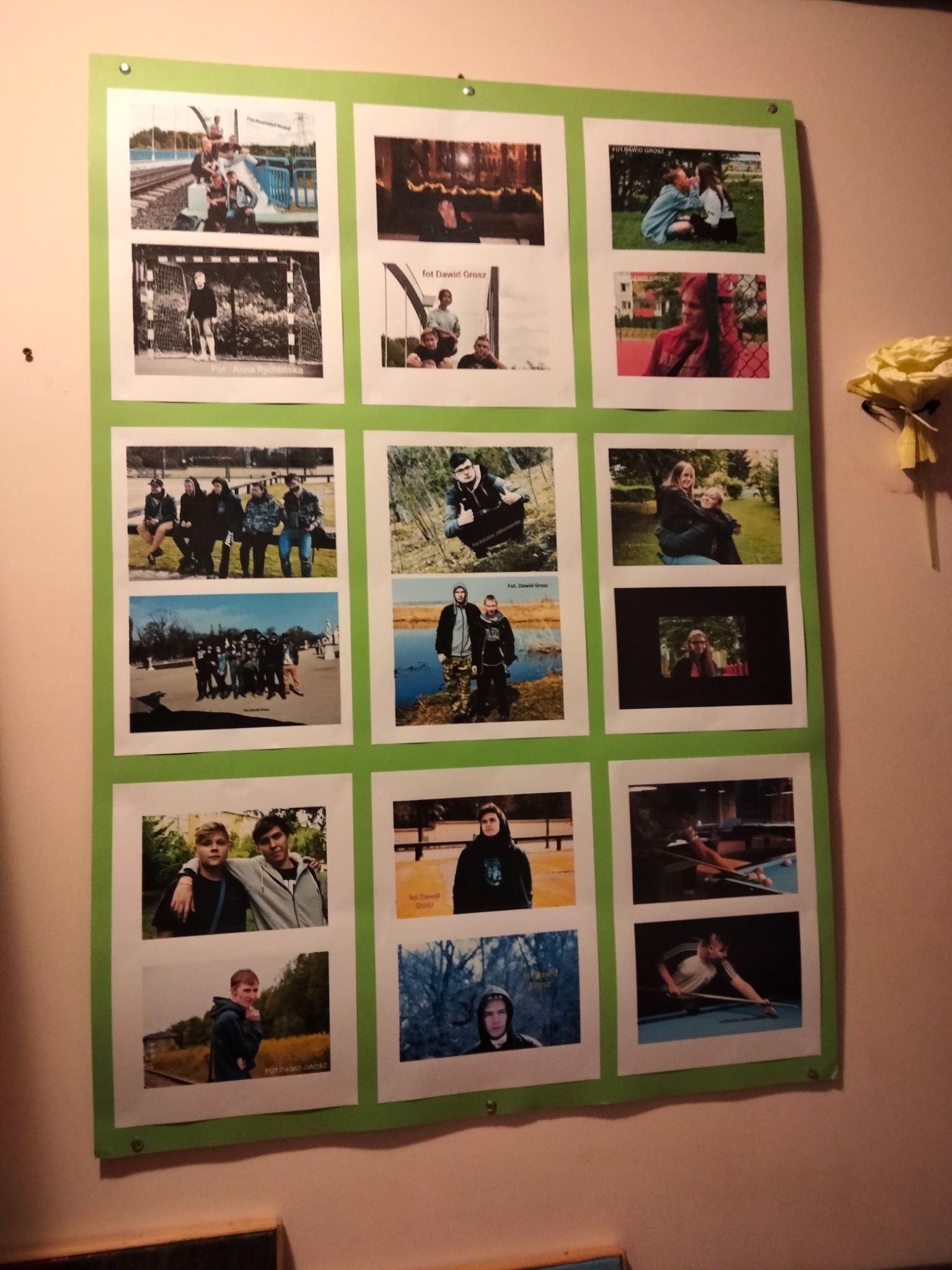 Tablica z kolekcją wydrukowanych, amatorskich fotografii portretowych i grupowych, przytwierdzona do ściany, niektóre zdjęcia podpisane imieniem fotografa.