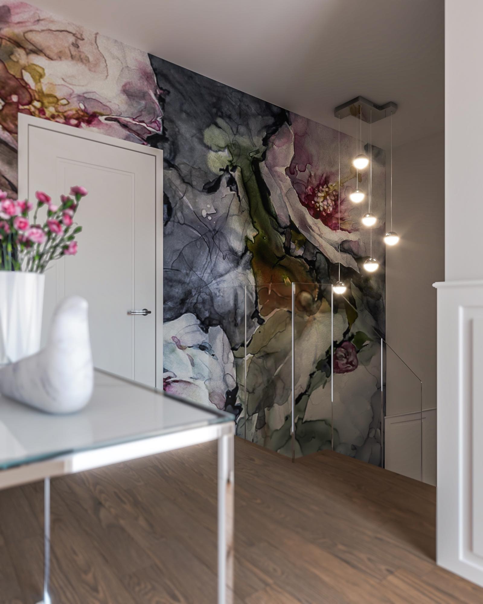 Nowoczesne wnętrze: białe drzwi, ściana z motywem akwarelowych kwiatów, szklany stolik z kwiatami i ceramiczną figurką ptaka, wiszące lampy kuliste nad schodami z drewnianymi stopniami.