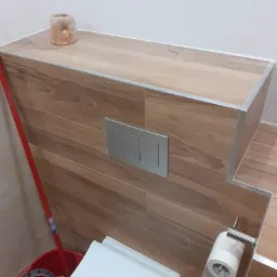 Wykończona toaleta z zabudowaną spłuczką, wykończona płytkami imitującymi drewno, z dekoracyjną lampką solną i widocznymi akcesoriami toaletowymi.