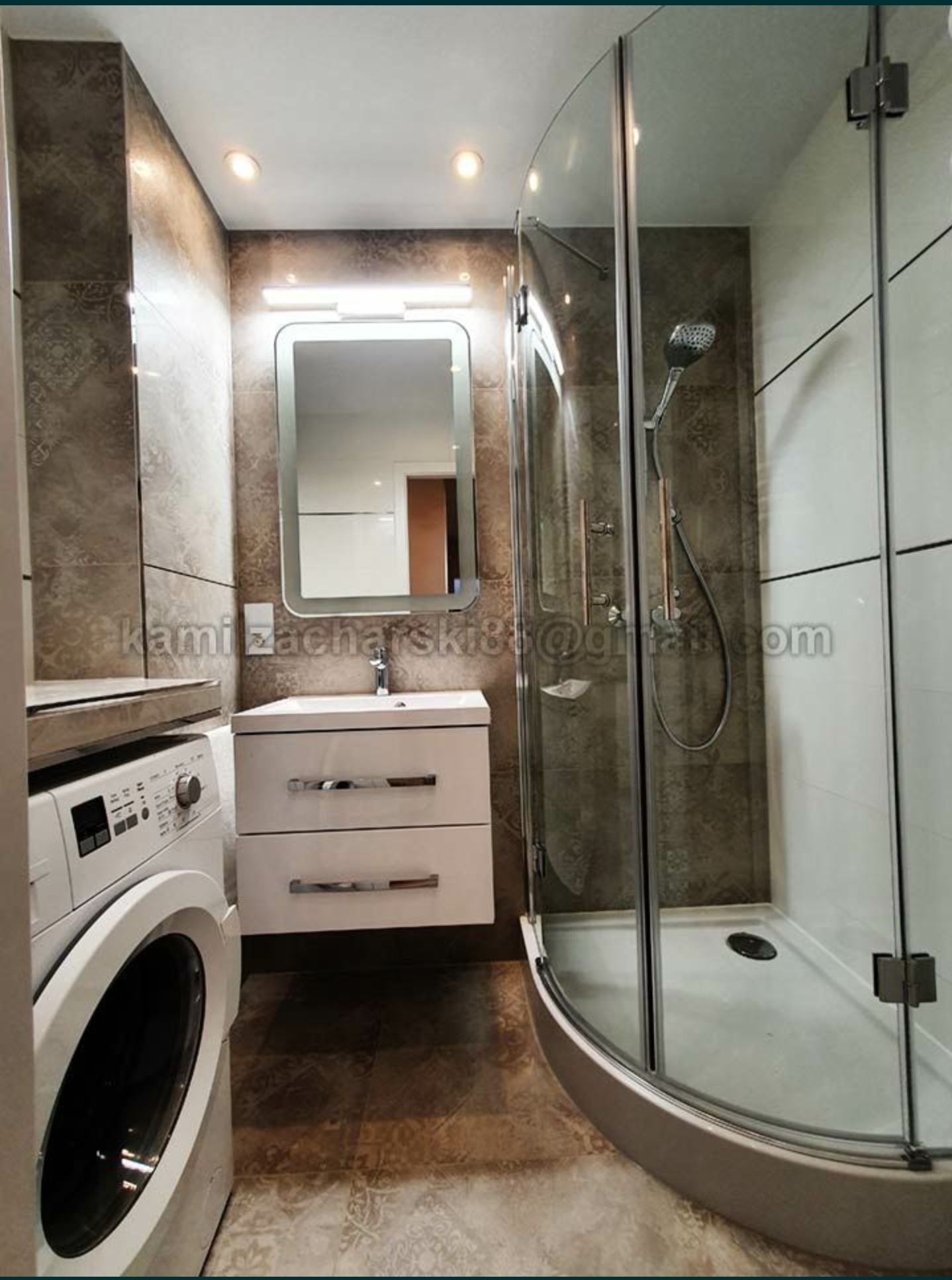 Nowoczesna łazienka z kabiną prysznicową, umywalką z szafką i pralką, wykończona brązowymi i białymi płytkami.