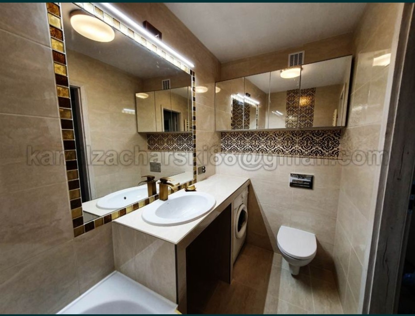 Jasna łazienka z beżowymi płytkami, lustrem z mozaikową ramą, białą umywalką i pralką pod blatem.