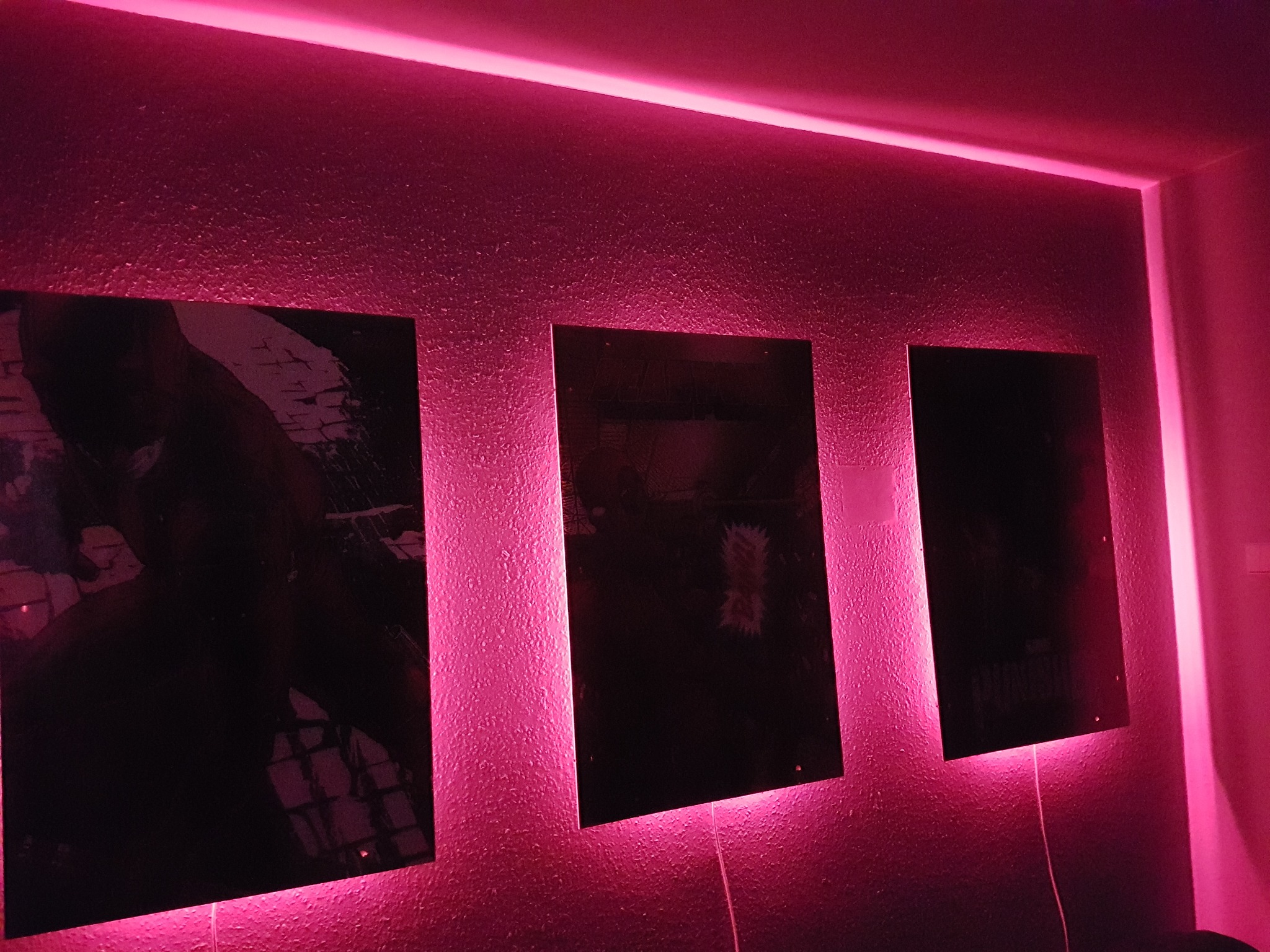 Trzy podświetlone różowym światłem obrazy na ścianie w Pułtusku, z widocznymi kablami zasilającymi i górnym paskiem LED.