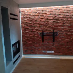 Wnętrze pokoju po remoncie: ściana z czerwonej cegły z podświetleniem LED, uchwyt TV, gładzie na ścianie z wnęką na kominek, parkiet na podłodze.