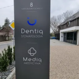 Szyld reklamowy przed budynkiem: Dentiq Stomatologia i Media Medycyna, adres 8 Merkuriusza Polskiego.