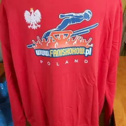 Czerwona bluza z nadrukiem skoczka narciarskiego, orła i napisu www.faniskokow.pl POLAND, prezentowana na manekinie.