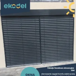 Zamknięte, antracytowe rolety zewnętrzne Z90 z napędem elektrycznym Somfy, zamontowane na elewacji budynku z widocznym logo firmy Eko-Del.