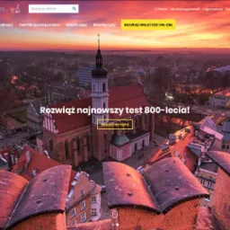 Strona internetowa Wielkiego Testu Wiedzy o Opolu z widokiem na miasto o wschodzie słońca, prezentująca quizy i materiały szkoleniowe związane z 800-leciem miasta.