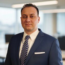 MIK Marek Gileta - Portret mężczyzny w garniturze na tle biura. Mężczyzna patrzy wprost, ma krótko ostrzyżone włosy i krawat w paski. W tle widoczne biurka i okna.