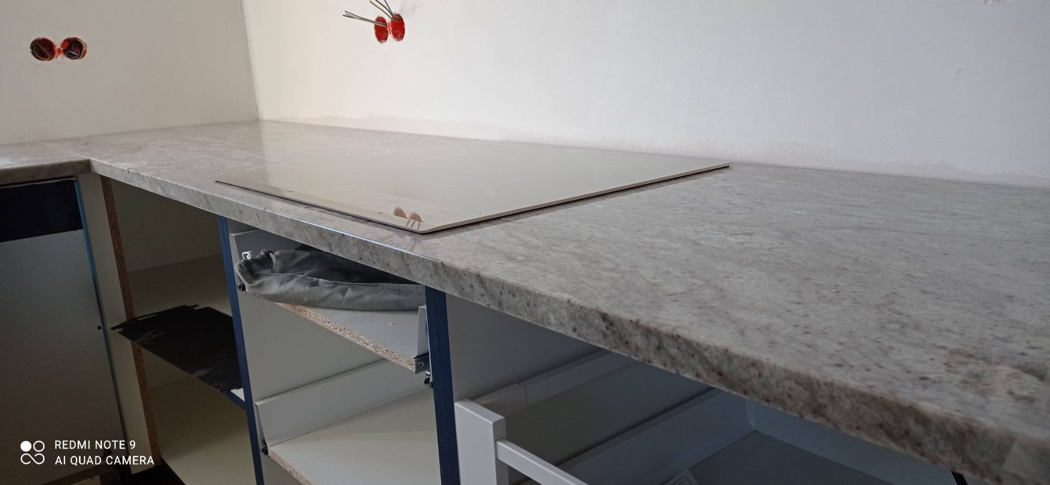 Szary blat kuchenny z wbudowaną płytą indukcyjną w trakcie montażu w Szczuczynie, widoczne niedokończone szafki i wystające kable elektryczne.