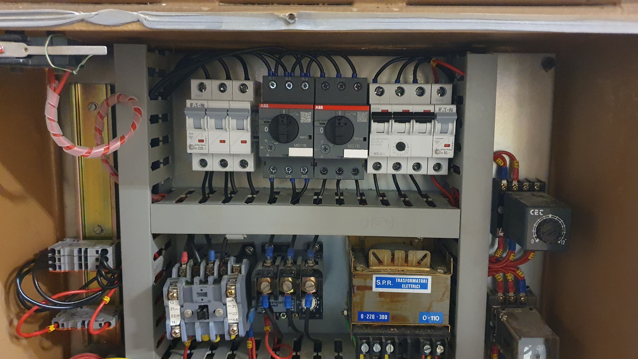 Rozdzielnica elektryczna z widocznymi bezpiecznikami Eaton, stycznikami ABB, transformatorem SPR i przekaźnikiem czasowym CEC, okablowanie wewnątrz szafy sterowniczej.