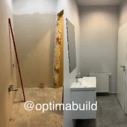 Porównanie stanu łazienki przed i po remoncie: surowe ściany z instalacją po lewej, wykończona umywalka z szafką, grzejnikiem i lustrem po prawej.