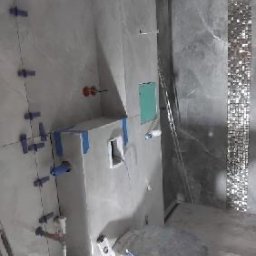 DOMINIX & ORIANIX & TRAIDING SPÓŁKA Z OGRANICZONĄ ODPOWIEDZIALNOŚCIĄ - Szara łazienka w trakcie remontu w Warszawie. Widoczne płytki imitujące marmur, niebieskie krzyżyki glazurnicze i zabudowa stelaża WC przed montażem ceramiki.