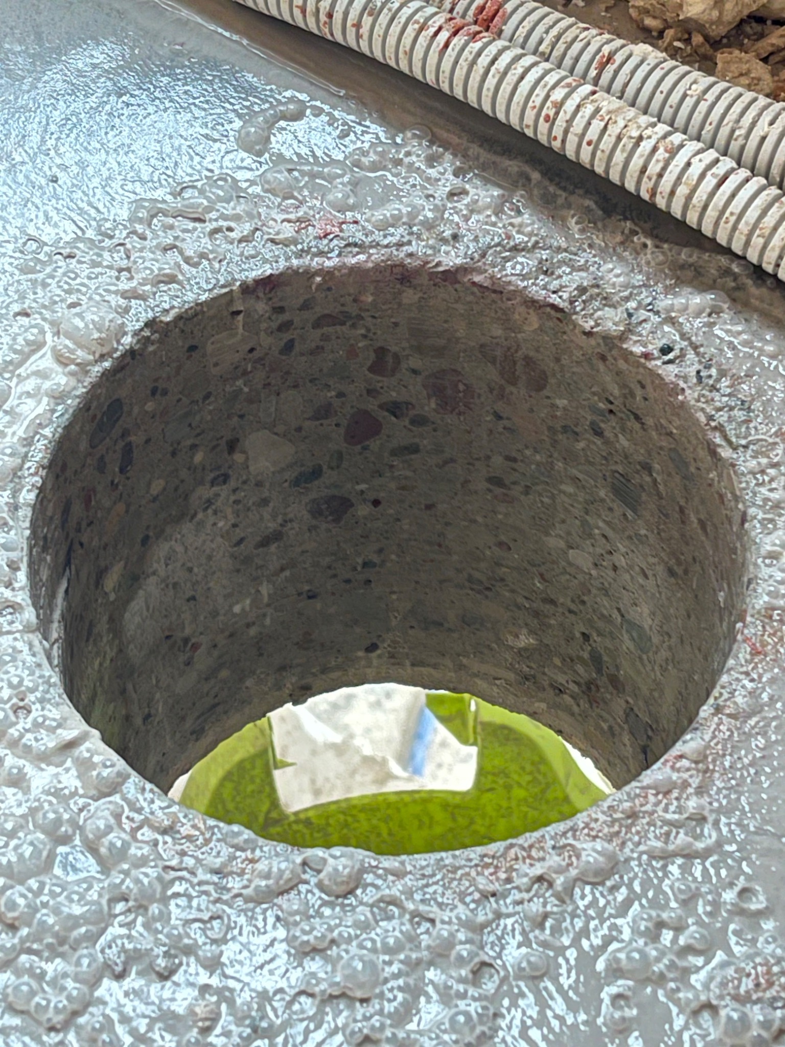 Wykonany w stropie żelbetonowym, zbrojonym prętami stalowymi, okrągły otwór po przewiercie koronką diamentową, widoczne ślady mokrego wiercenia i fragment węża doprowadzającego wodę chłodzącą,...