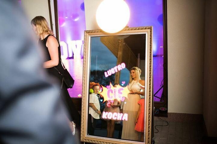 Osoby pozują do zdjęcia w interaktywnym lustrze z nakładanymi efektami świetlnymi i napisami podczas imprezy.