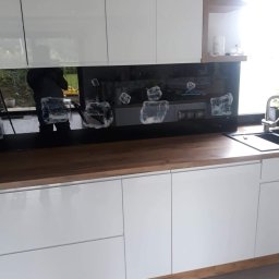 Grzegorz - Szklany panel dekoracyjny z motywem geometrycznym, zamontowany nad blatem kuchennym z drewnianym wykończeniem, w nowoczesnej kuchni z białymi szafkami.