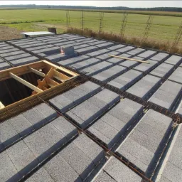 Wieniec stropowy z szalunkiem traconym i zbrojeniem stalowym, widok z góry na budowę domu jednorodzinnego, w tle pole uprawne.