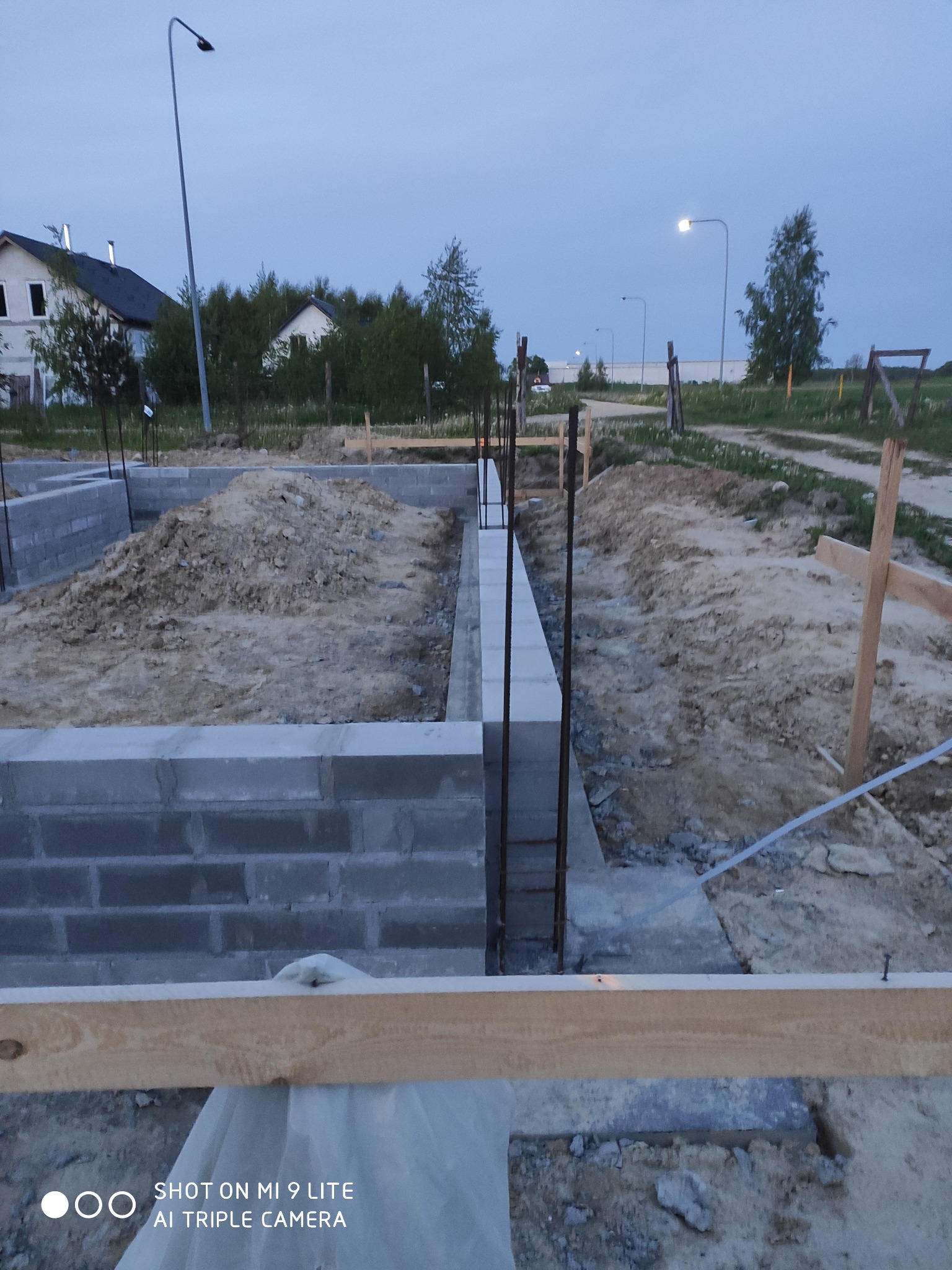 Budowa fundamentów pod dom jednorodzinny w Chojnicach, widoczne bloczki betonowe i wystające pręty zbrojeniowe, teren budowy w trakcie prac ziemnych, w tle zabudowa mieszkalna.