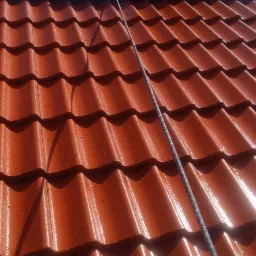 Czerwona dachówka ceramiczna, połowa dachu umyta, widoczna różnica w czystości i kolorze, lina na dachu, perspektywa z dołu.