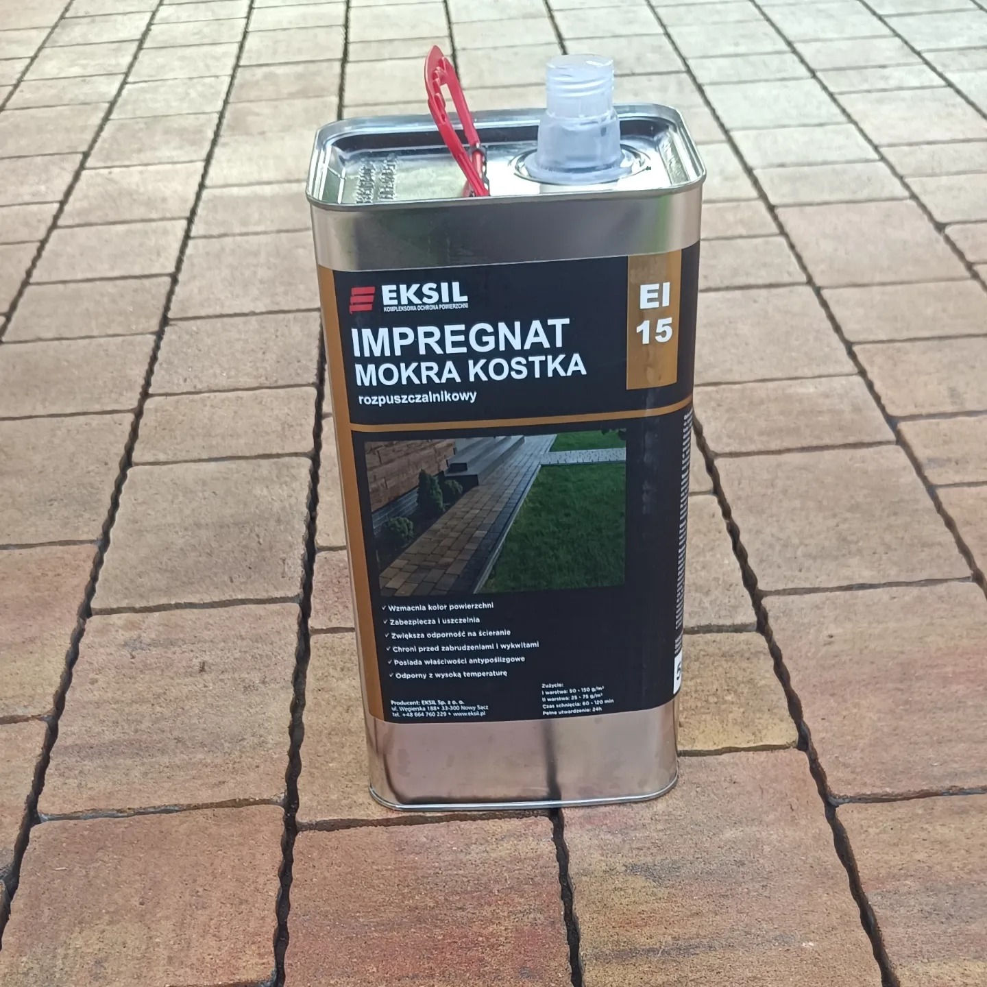 Puszka z impregnatem do kostki brukowej firmy Eksil, ustawiona na kostce brukowej. Widoczny napis 'Impregnat Mokra Kostka' oraz właściwości produktu.