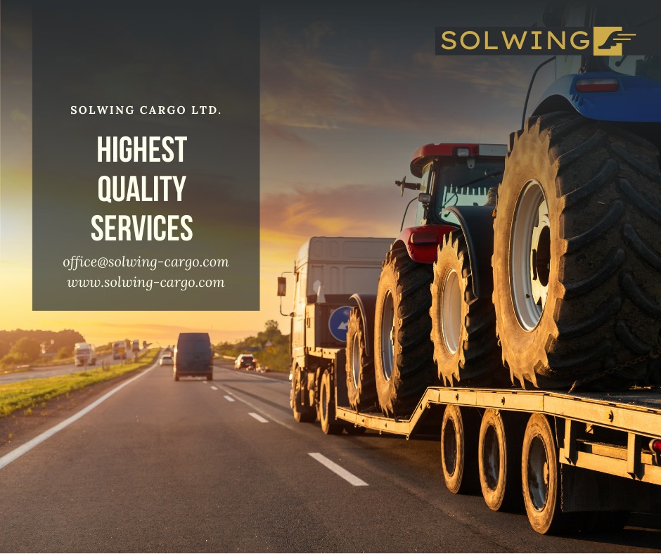 Ciężarówka na lawecie transportuje traktor po autostradzie o zachodzie słońca, logo firmy Solwing Cargo Ltd. w tle.