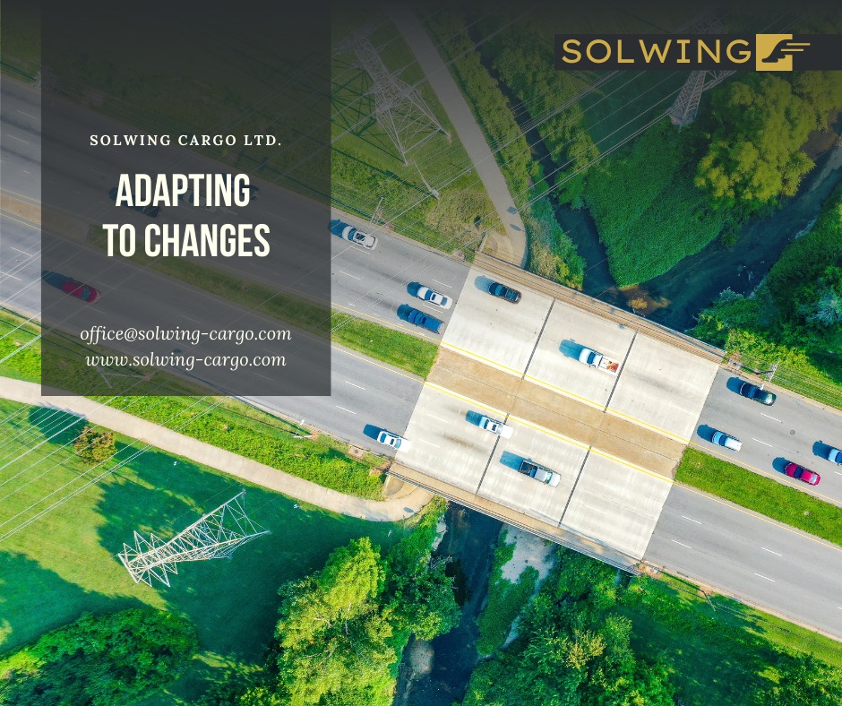 Widok z lotu ptaka na ruchliwy most autostradowy otoczony zielenią, z logo Solwing Cargo i hasłem 'Adapting to Changes'.