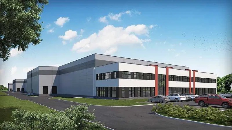 Wizualizacja zewnętrzna nowoczesnego budynku magazynowo-biurowego z parkingiem wypełnionym samochodami osobowymi i pickupem, na tle błękitnego nieba z chmurami.
