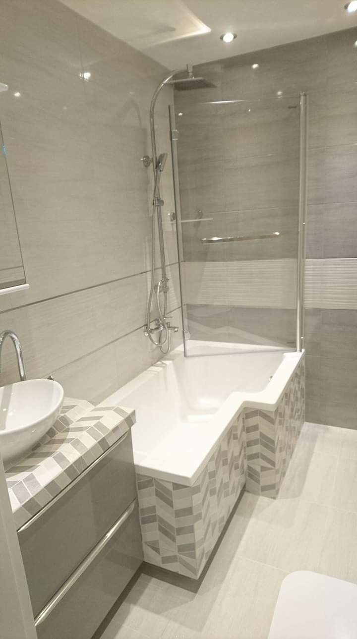 Nowoczesna łazienka po remoncie: wanna z parawanem nawannowym, umywalka nablatowa na szafce z mozaiką, szara płytka ścienna i podłogowa.