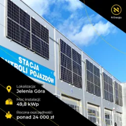 Panele fotowoltaiczne zamontowane na elewacji budynku Stacji Kontroli Pojazdów w Jeleniej Górze, z informacją o mocy instalacji 49,8 kWp i rocznej oszczędności ponad 24 000 zł.