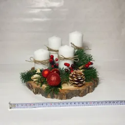 Dekoracja świąteczna z czterema białymi świecami owiniętymi sznurkiem, ułożona na plastrze drewna z gałązkami świerku, czerwonymi bombkami i szyszką; w tle białe tło ze wzorem śnieżynek,...