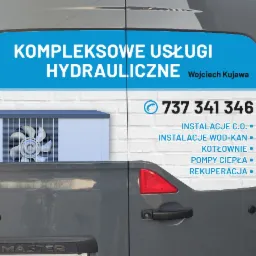 Grafika reklamowa na tylnych drzwiach szarego samochodu dostawczego, prezentująca ofertę kompleksowych usług hydraulicznych firmy Wojciech Kujawa, z numerem telefonu i listą usług: instalacje C.