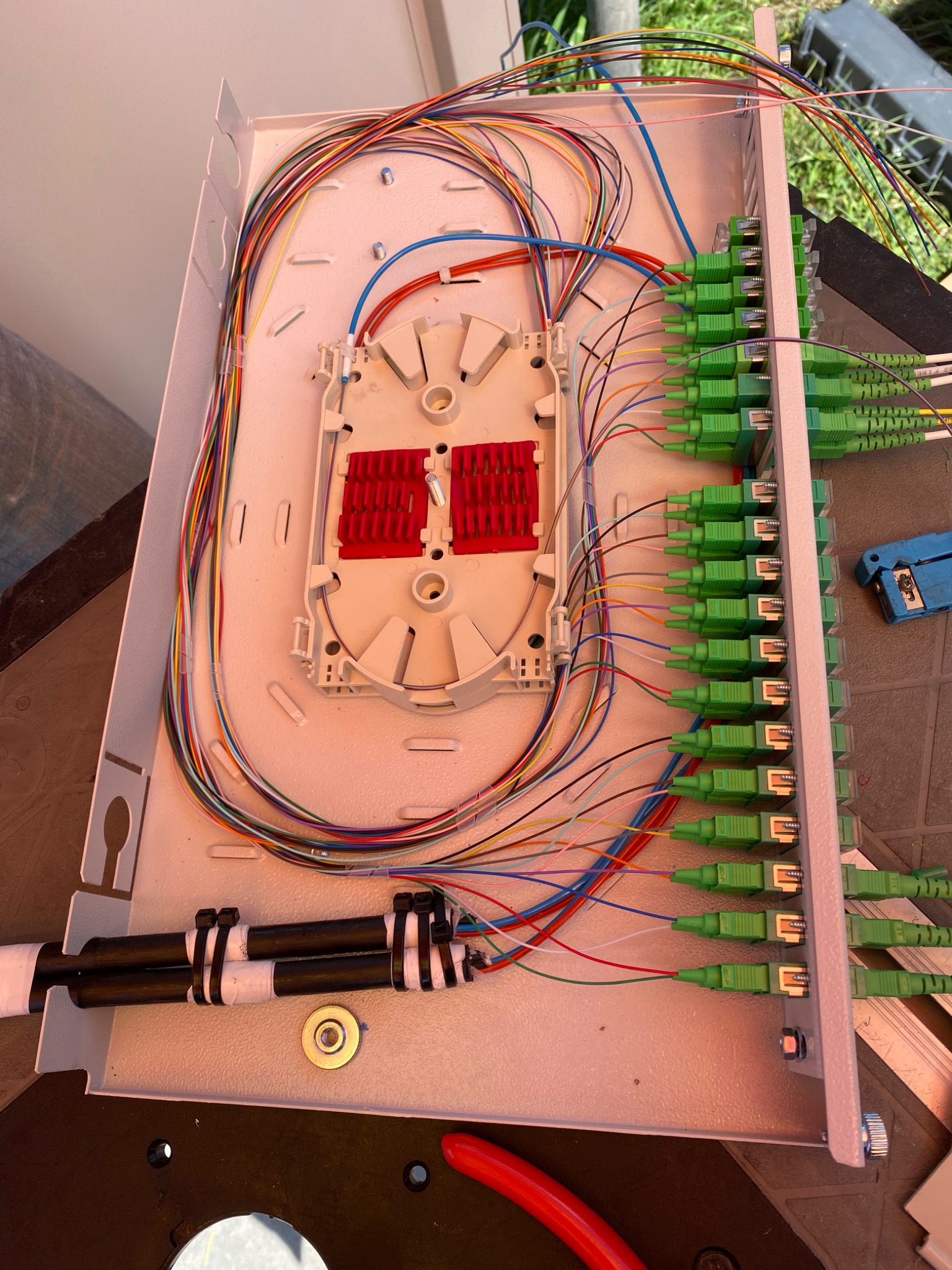 Rozdzielnica światłowodowa z precyzyjnie ułożonymi kablami i zielonymi złączami, zainstalowana w Morawach, widok z góry na wnętrze skrzynki.