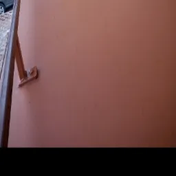 Fragment pomalowanego na brązowo dachu z widocznym mocowaniem rynny i fragmentem rynny, z samochodem w tle.