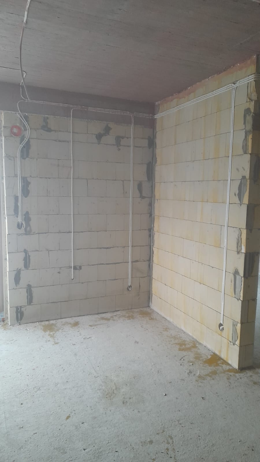 Surowy stan wnętrza w Konstancin-Jeziorna z widocznymi przewodami elektrycznymi poprowadzonymi po ścianach z bloczków, przygotowanymi do dalszych prac wykończeniowych.