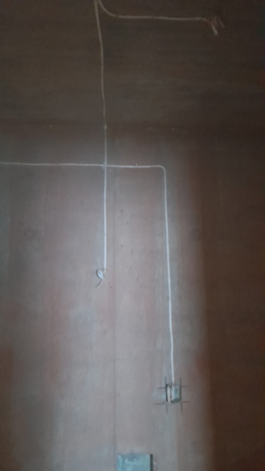 Ściana w trakcie remontu z poprowadzonymi przewodami elektrycznymi w białych rurkach, widoczna puszka pod gniazdko.