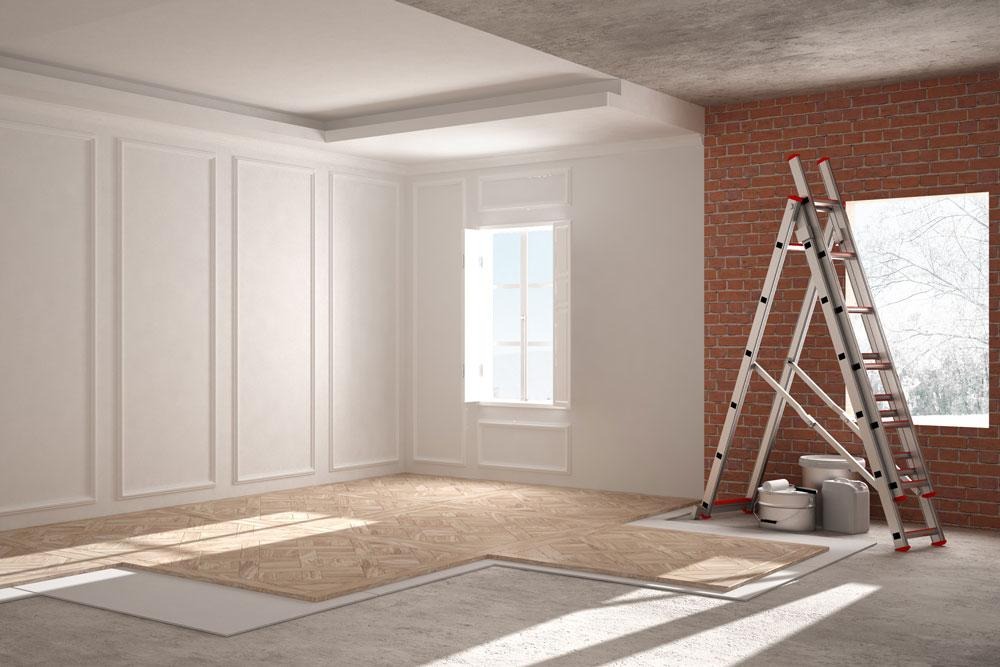 Wnętrze w trakcie prac wykończeniowych: częściowo ułożony parkiet w jodełkę, drabina oparta o ścianę z cegły, widoczne puszki i wiaderka z materiałami budowlanymi.