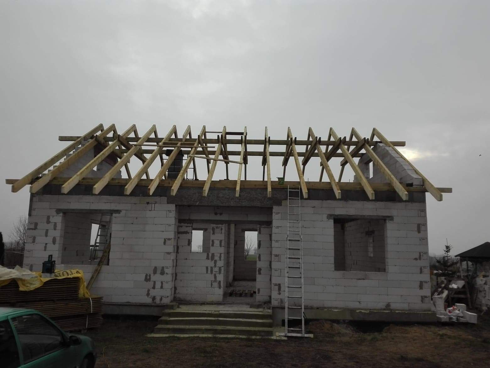 Konstrukcja drewniana dachu w trakcie budowy domu z białego bloczka, widoczna drabina oparta o ścianę, Bieżyń.