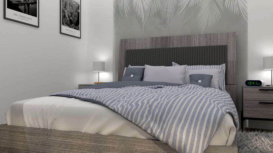 Nowoczesna sypialnia z łóżkiem z szarym wezgłowiem, pościel w niebiesko-białe paski, plakaty San Francisco i Nowego Jorku na ścianie, tapeta z motywem liści palmowych oraz cyfrowy zegar na szafce...