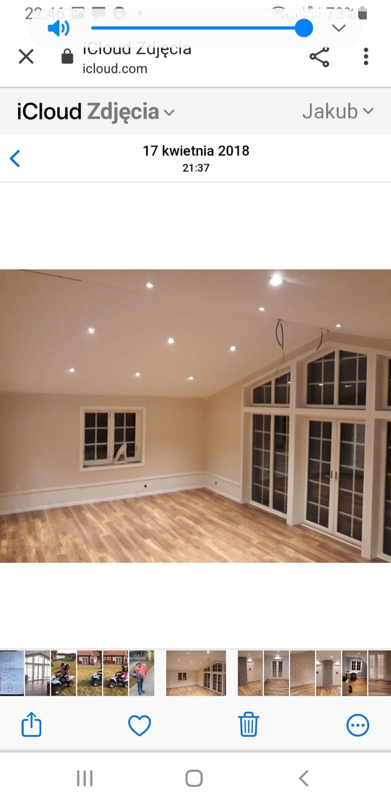 Jasne wnętrze z drewnianą podłogą, białymi ścianami i oknami, z widocznymi punktowymi lampami sufitowymi i wystającymi kablami.