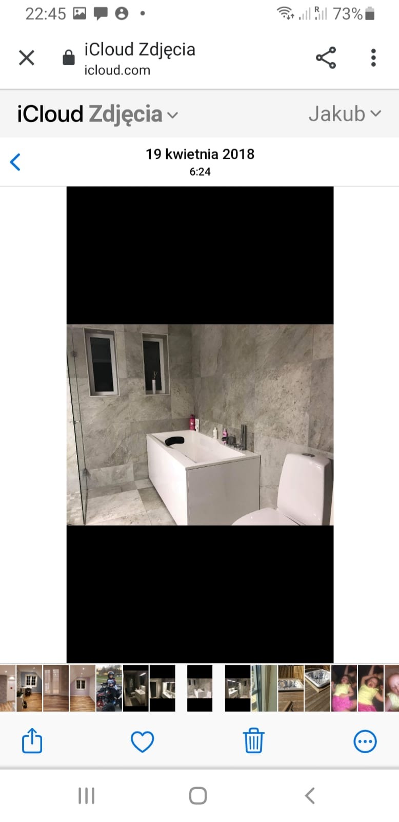 Nowoczesna łazienka z wanną obudowaną białą płytą, szarą marmurową okładziną ścian i podłogi, oraz przeszkloną kabiną prysznicową