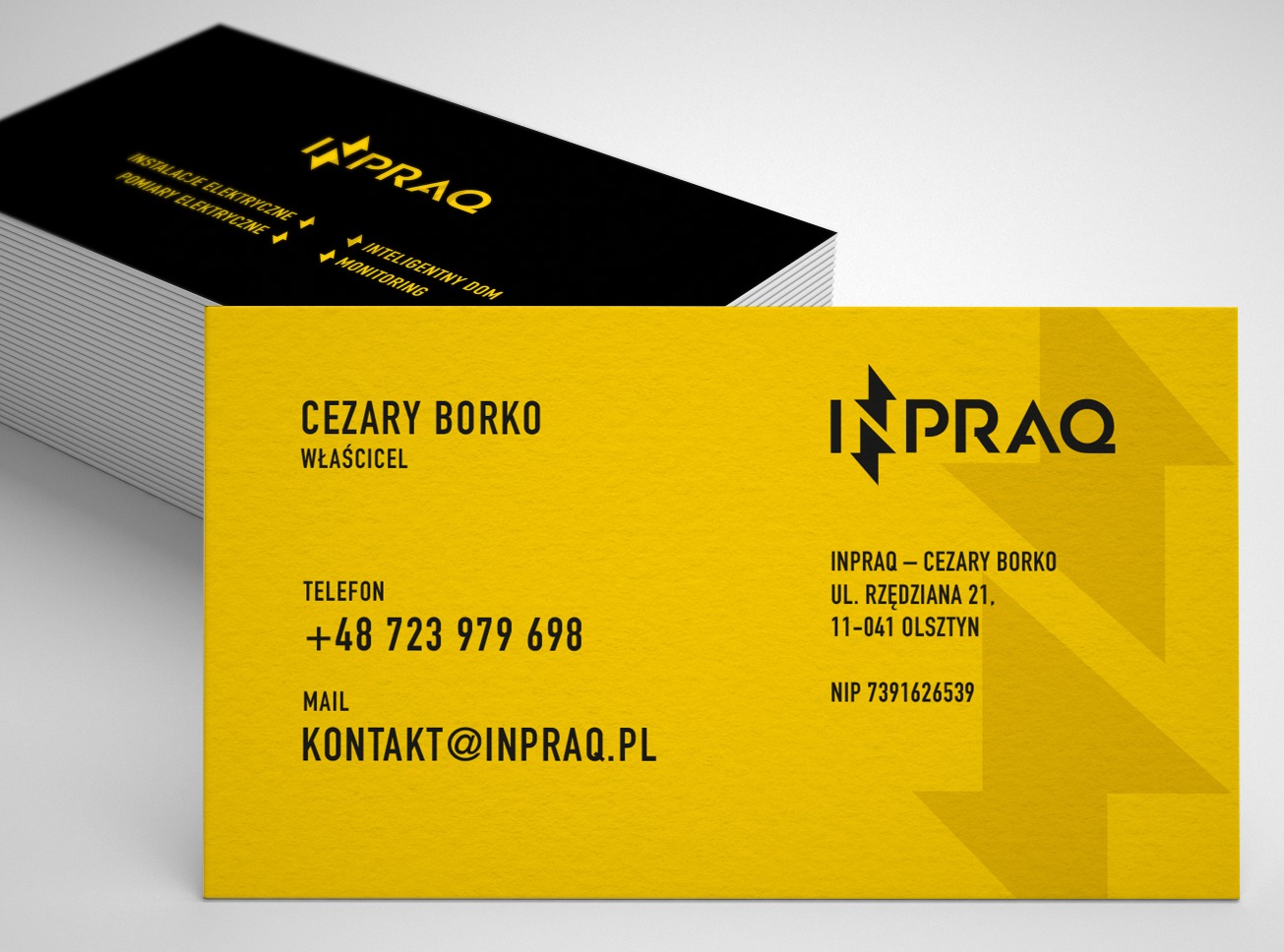 Żółto-czarne wizytówki firmy INPRAQ, oferującej usługi elektryczne i monitoring, ułożone w stos na jasnym tle. Widoczne dane kontaktowe Cezarego Borko, właściciela firmy, oraz adres i NIP.