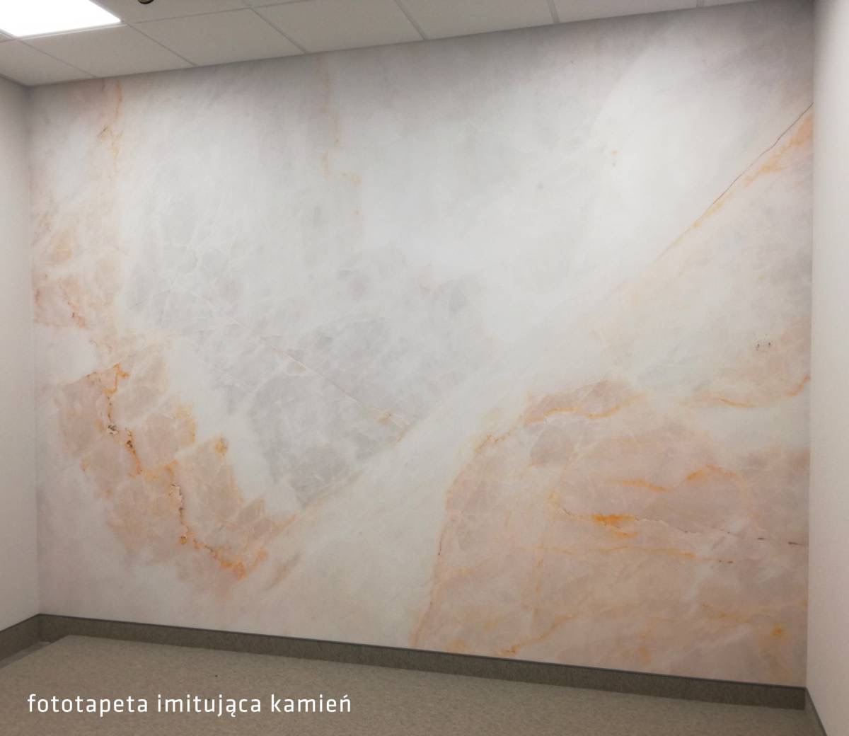 Fototapeta imitująca marmur w jasnych odcieniach bieli i różu, pokrywająca całą ścianę w pomieszczeniu biurowym, widoczna z perspektywy narożnika.